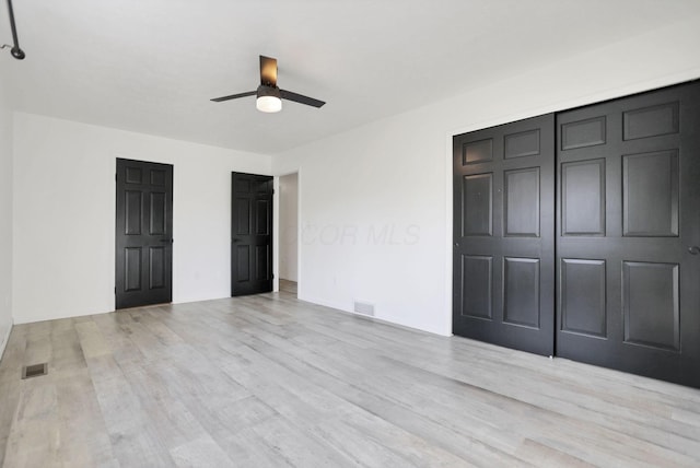 unfurnished bedroom featuring light wood-type flooring, a closet, and ceiling fan