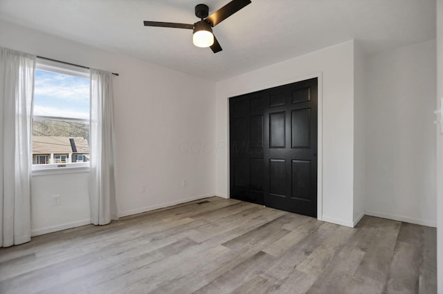 unfurnished bedroom with multiple windows, light wood-type flooring, a closet, and ceiling fan