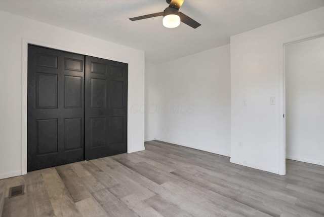 unfurnished bedroom with ceiling fan, a closet, and light wood-type flooring