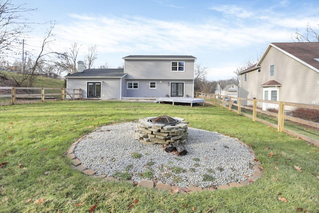 rear view of house featuring a lawn, a deck, and an outdoor fire pit