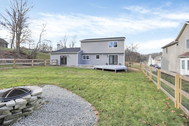 rear view of house featuring a fire pit, a deck, and a lawn