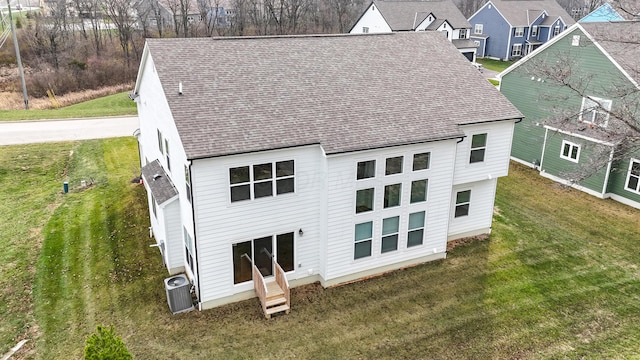 back of house with cooling unit and a lawn