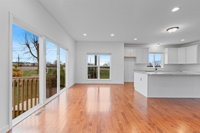 kitchen with white cabinets, a wealth of natural light, and light hardwood / wood-style flooring