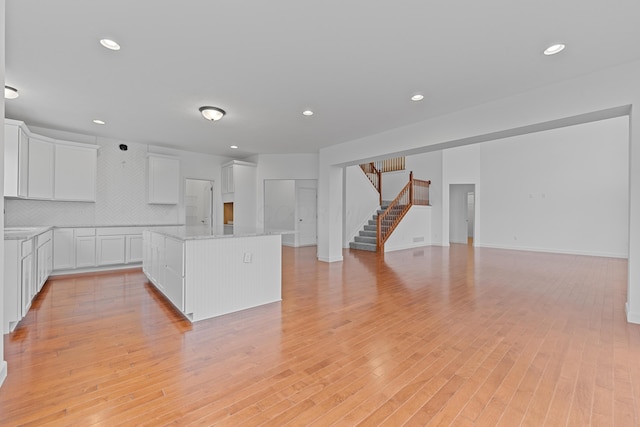 kitchen featuring tasteful backsplash, light stone counters, white cabinets, and light hardwood / wood-style floors