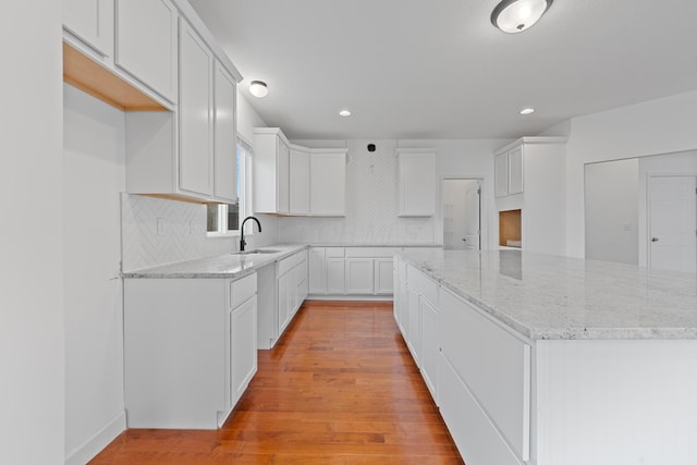 kitchen featuring tasteful backsplash, sink, light hardwood / wood-style flooring, white cabinets, and a center island