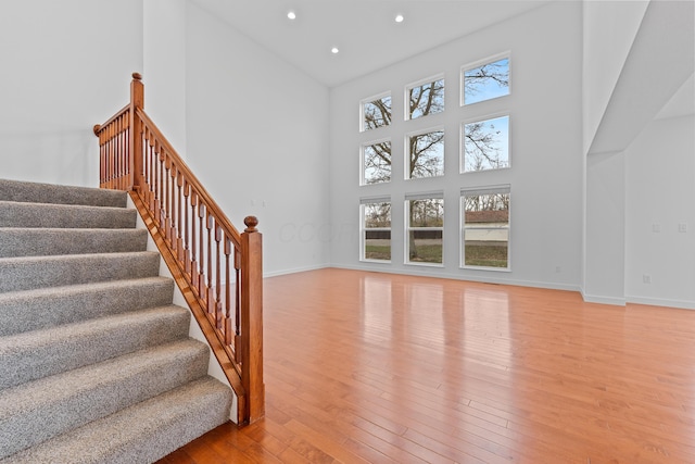 stairs featuring hardwood / wood-style floors and a high ceiling