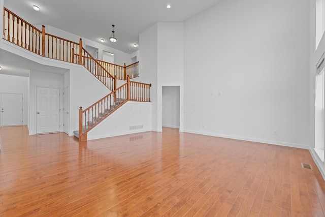 unfurnished living room with light hardwood / wood-style floors and a high ceiling