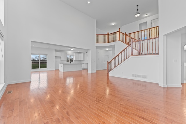 unfurnished living room with a towering ceiling and light hardwood / wood-style flooring