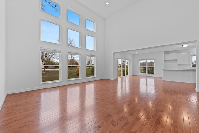 unfurnished living room featuring a high ceiling and light hardwood / wood-style floors