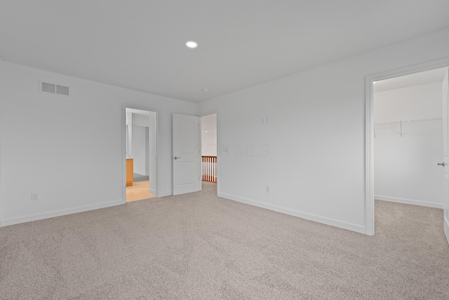 unfurnished bedroom featuring light carpet, a spacious closet, and a closet