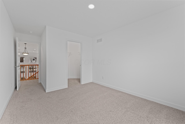 unfurnished bedroom featuring a spacious closet, a closet, and light carpet