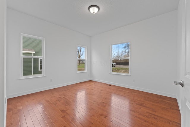 spare room featuring a wealth of natural light and hardwood / wood-style floors