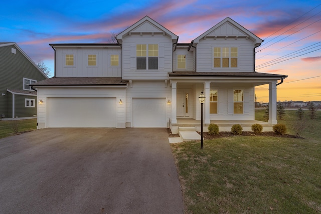 view of front of house featuring a lawn, covered porch, and a garage