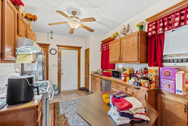 kitchen featuring a textured ceiling, ceiling fan, dishwasher, light hardwood / wood-style floors, and white gas stove