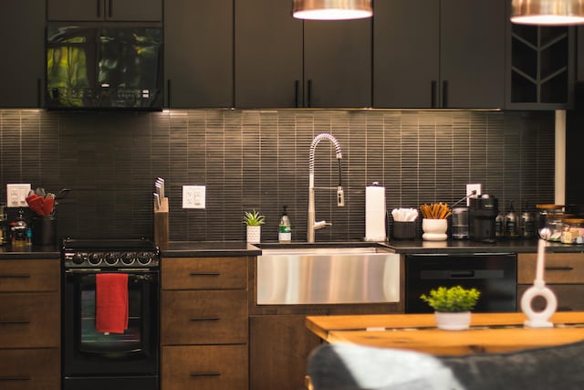 kitchen with black appliances, decorative backsplash, and sink