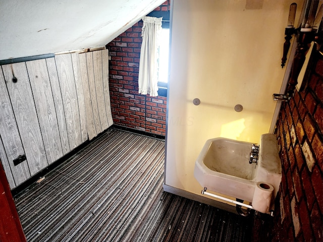 bathroom with vaulted ceiling and brick wall