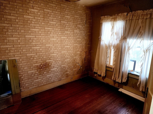 empty room with dark wood-type flooring and brick wall