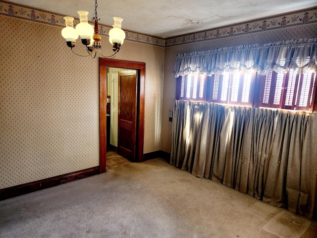 carpeted empty room with a notable chandelier and a textured ceiling