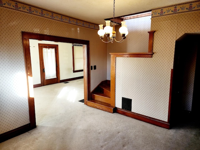 spare room with a notable chandelier, carpet floors, and a textured ceiling