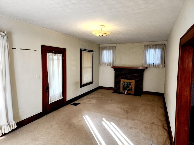 unfurnished living room with a fireplace, carpet, a healthy amount of sunlight, and a textured ceiling