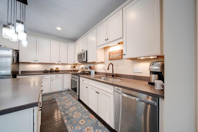 kitchen with dark hardwood / wood-style floors, sink, white cabinets, hanging light fixtures, and stainless steel appliances