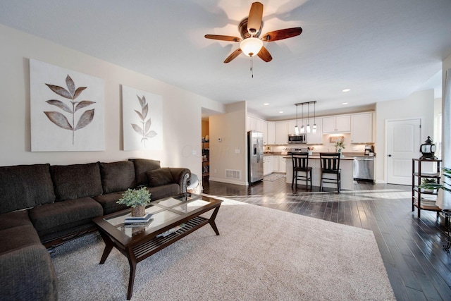 living room with dark wood-type flooring and ceiling fan