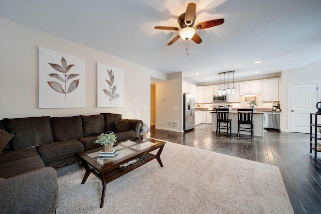 living room featuring ceiling fan and dark hardwood / wood-style flooring