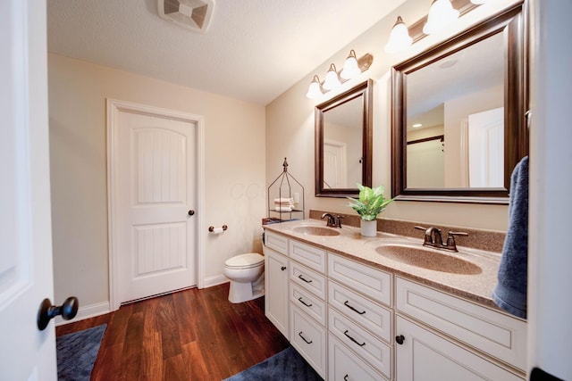 bathroom with vanity, hardwood / wood-style flooring, a textured ceiling, and toilet