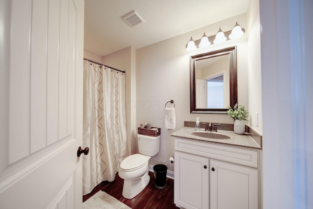 bathroom featuring wood-type flooring, vanity, a textured ceiling, and toilet