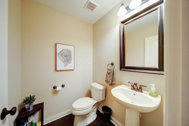 bathroom featuring wood-type flooring, toilet, and sink