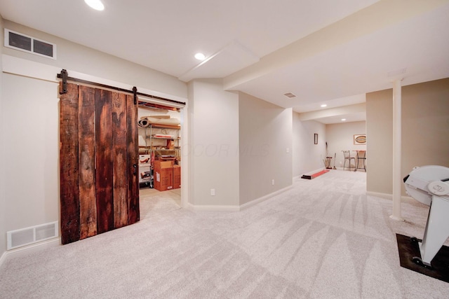 basement featuring light colored carpet and a barn door