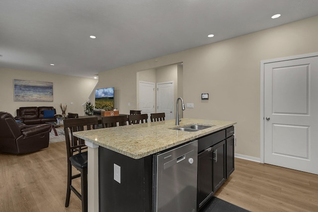 kitchen featuring stainless steel dishwasher, a center island with sink, sink, and light hardwood / wood-style flooring