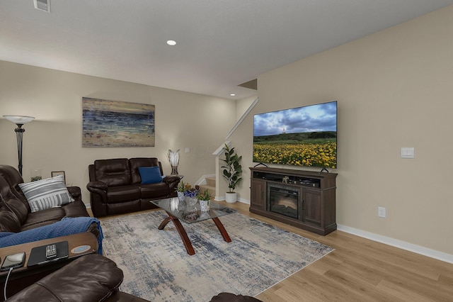 living room with a fireplace and light wood-type flooring