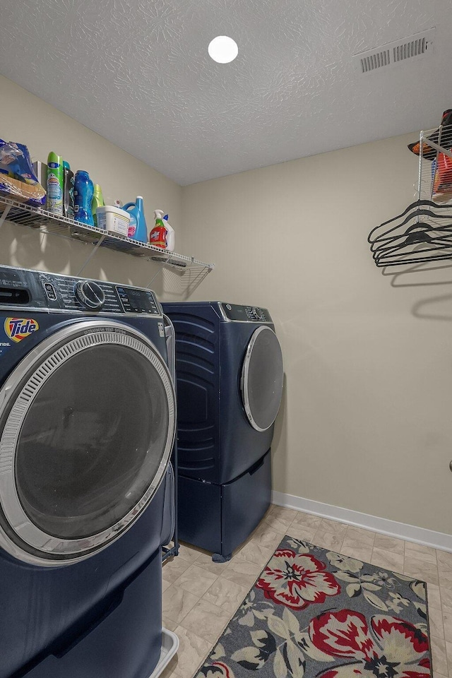 laundry area featuring washing machine and clothes dryer and a textured ceiling