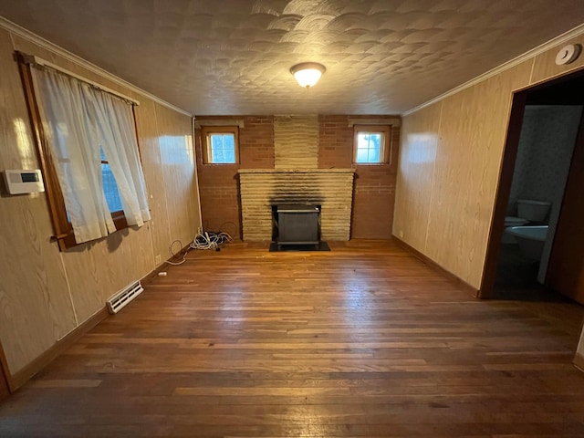 unfurnished living room with dark hardwood / wood-style flooring, crown molding, and wood walls