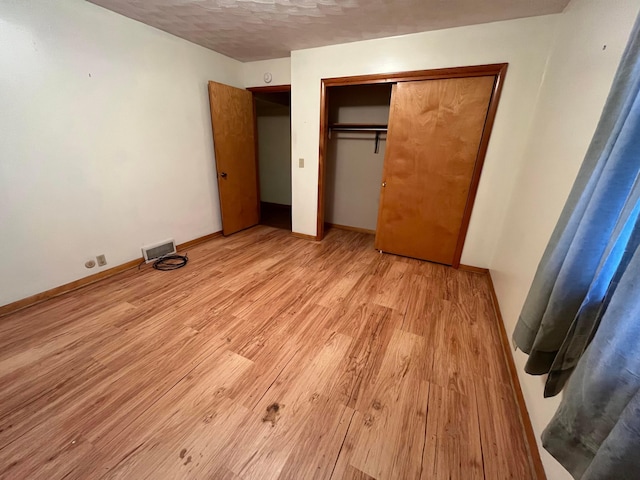 unfurnished bedroom with a closet, light hardwood / wood-style floors, and a textured ceiling