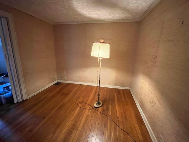 empty room featuring crown molding and hardwood / wood-style flooring