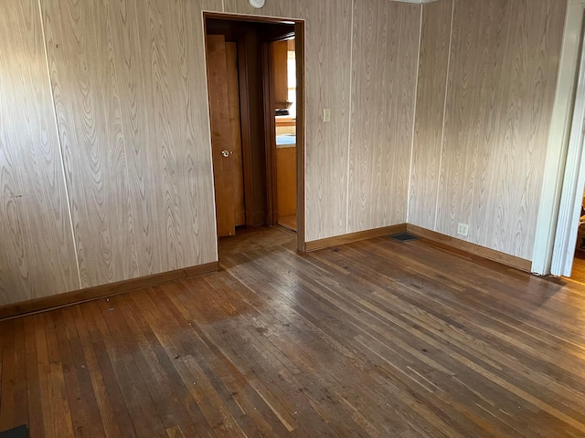 spare room with wooden walls and dark wood-type flooring