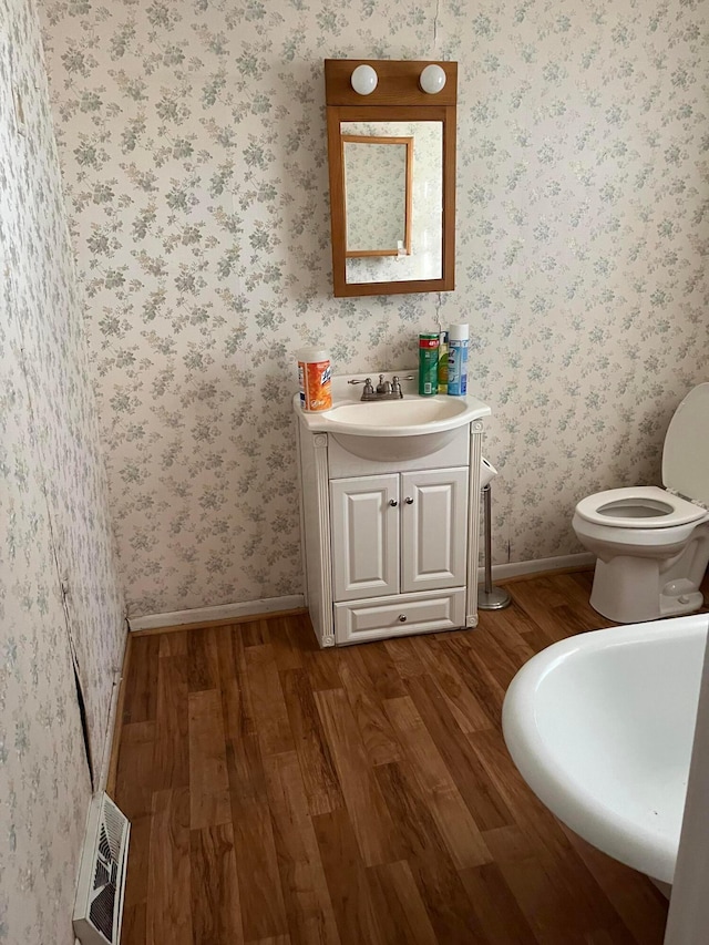 bathroom with hardwood / wood-style floors, vanity, and toilet