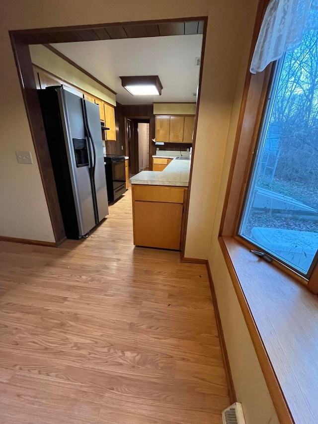 kitchen with sink, black electric range oven, stainless steel refrigerator with ice dispenser, kitchen peninsula, and light wood-type flooring