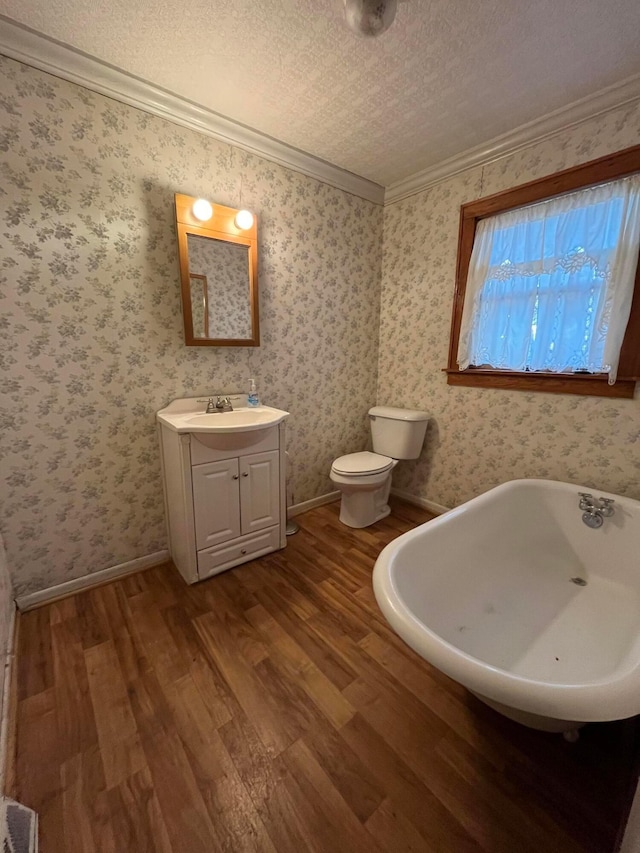 bathroom with a textured ceiling, toilet, wood-type flooring, and ornamental molding