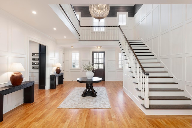 entrance foyer featuring a notable chandelier, ornamental molding, and light wood-type flooring