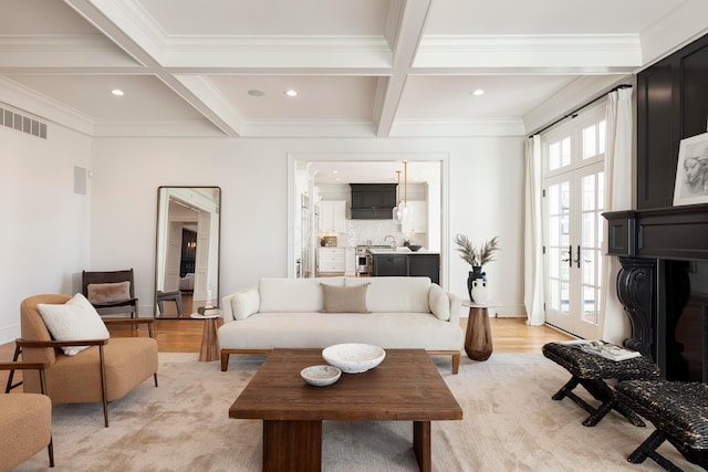 living room featuring crown molding, light hardwood / wood-style flooring, coffered ceiling, french doors, and beamed ceiling