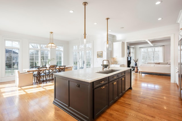 kitchen with pendant lighting, white cabinetry, sink, dark brown cabinets, and light hardwood / wood-style flooring