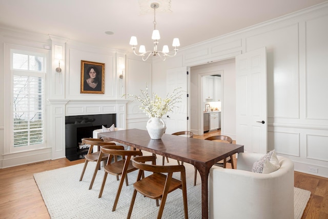 dining room featuring a notable chandelier, crown molding, light hardwood / wood-style flooring, and sink