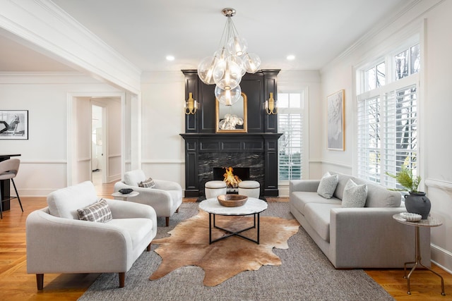 living room featuring hardwood / wood-style flooring, ornamental molding, a chandelier, and a high end fireplace