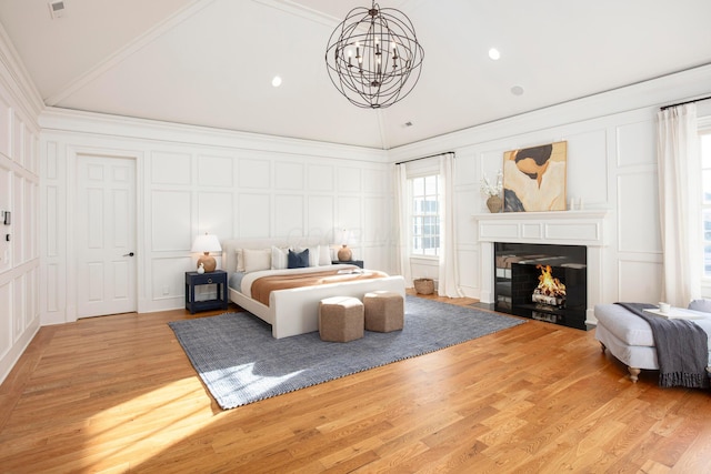 bedroom featuring vaulted ceiling, ornamental molding, a chandelier, and light wood-type flooring