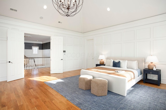 bedroom with crown molding, a notable chandelier, hardwood / wood-style flooring, and lofted ceiling