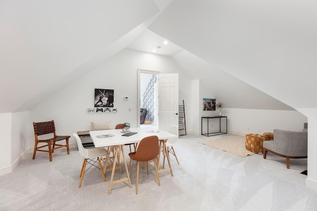 dining room with lofted ceiling and light carpet