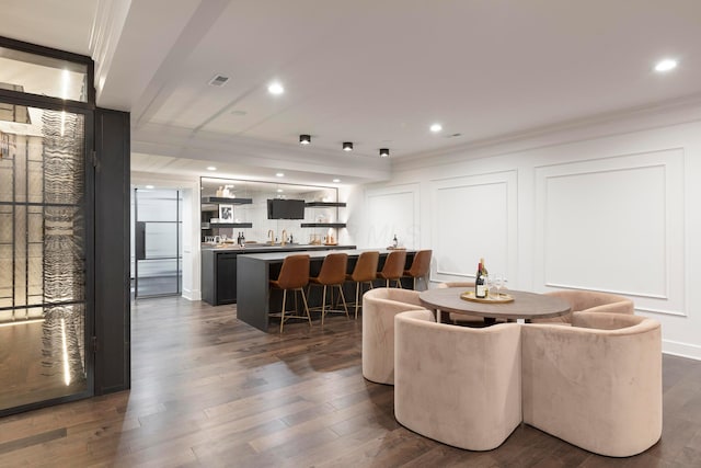 dining room featuring crown molding, bar, and dark hardwood / wood-style flooring